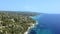 Open blue tranquil sea and a rocky coast on the left side covered by pine trees and rocks. Aerial view