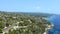 Open blue tranquil sea and a rocky coast on the left side covered by pine trees and rocks. Aerial view