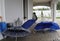 Open blue umbrellas on the terrace of a luxury villa with white garden furniture and white walls and stone floor.