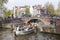 Open boat full of young people under bridge in amsterdam canal o