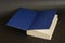 Open book on a black background. Textbook with blue endpapers. H