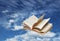 Open book flying on blue sky