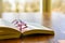 Open book and glasses on a wooden table with sunlight