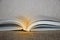 Open book with light beam on it on canvas background
