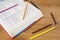 An open book and many colored pencils on a wood table