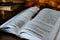 Open book with pen with pen against the background of a stack of books and warm evening bokeh