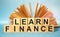 Open book and Wooden cubes with the abbreviation LEARN FINANCE