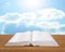 Open book on wooden plank bright sky background