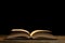 Open book on a wooden table night mood on black background with copy space for your text