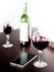 Open bottle and two glasses of red wine and a mobile phone on brown wodden table and white blurred wall background. Alcohol drink