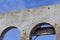 Open brick arches from an abandoned building, white with rusty metal against a blue sky