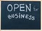 Open for business sign message handwritten with white chalk on on wooden frame blackboard