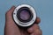 Open camera lens in a hand on a blue background