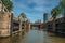 Open canal sluice gate, bridge and building under sunny blue sky in Amsterdam.