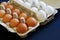 Open cardboard boxes with white and brown chicken eggs lie on a blue background. Choice and variety. Close-up