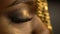 Open and closed eyes with bronze eyeshadows and cat eyes on the face of african girl wearing golden jewellery on her