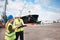 Open communication brings results. Two dock workers holding paperwork while standing in the shipyard.