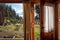 An open door seen from the interior of a wooden cozy and relaxing cabin that leads to the forest and lake. Concept of