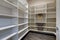 Open door to empty pantry room with white shelves