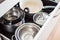 Open drawer of cabinet with steel pots and pans