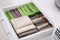 Open drawer with different folded towels and napkins in kitchen, closeup