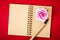 Open empty diary and pen with rose on red.