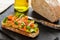 Open faced sandwich with smoked salmon, avocado, apple, zucchini, pumpkin, basil and chives on toasted sourdough bread. With knife