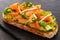 Open faced sandwich with smoked salmon, avocado, apple, zucchini, pumpkin, basil and chives on toasted sourdough bread on slates.