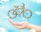 Open female hand with Bicycle wood icon with blue sky and cloud, Healthy lifestyle concept