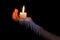 Open hand holding candle stick with wax flowing down the arm