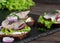 Open herring sandwich - traditional Danish smorrebrod. Sandwiches are located on a stone tray, a dark wooden background. Close-up