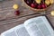 Open Holy Bible Book of Galatians with fresh red and yellow cherries in a wicker basket on a wooden table