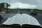 Open Holy Bible in Psalm 91. Windshield with raindrops. Blurred background with expressway.