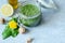 Open jar vegan dandelion pesto with garlic, lemon, olive oil and walnut on a gray background.