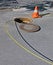 Open manhole with yellow optic cables,