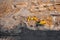 Open mine of gold, diamonds, coal. Industrial landscape with large yellow dump trucks and excavators