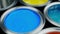 Open multicolor paint cans on grey background, top view