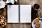 An open notebook with blank pages on wood table.Cup of tea, nuts and biscuits snack