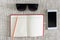 Open notebook, smartphone, sunglasses on clean sackcloth with wood pencil