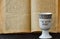 An open old Jewish Bible and white porcelain kiddush wine cup with inscription: Creator of the fruit of the vine