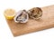 An open oyster and a closed oyster on a wooden board