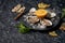 Open oysters lying on crushed ice with lemon, peppermint, with a knife for opening oysters on a dark textured stone background.