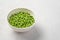 Open peas with a white bowl on a gray background.