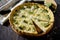 Open pie quiche Lauren with broccoli and cheese on a dark wooden table