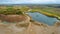 Open pit gravel mining site with lake or pond of unusual shape and beautiful autumn nature, gravel piles photographed with drone