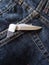 Open pocket knife in blue jeans