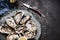 Open raw oysters on vintage plate with lemon and oysters knife, dark background, top view