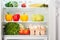 Open refrigerator full of fruits and vegetables