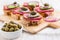 Open roast beef sandwiches with vegetables, olives and capers