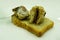 Open sandwich made of brown sprouted bread, slices of fillet of pickled Atlantic herring and green olives on a saucer closeup at